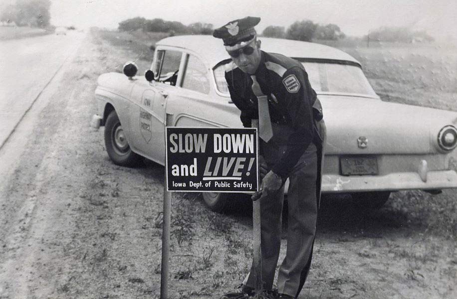 1957 Iowa police officer placing speed warning sign